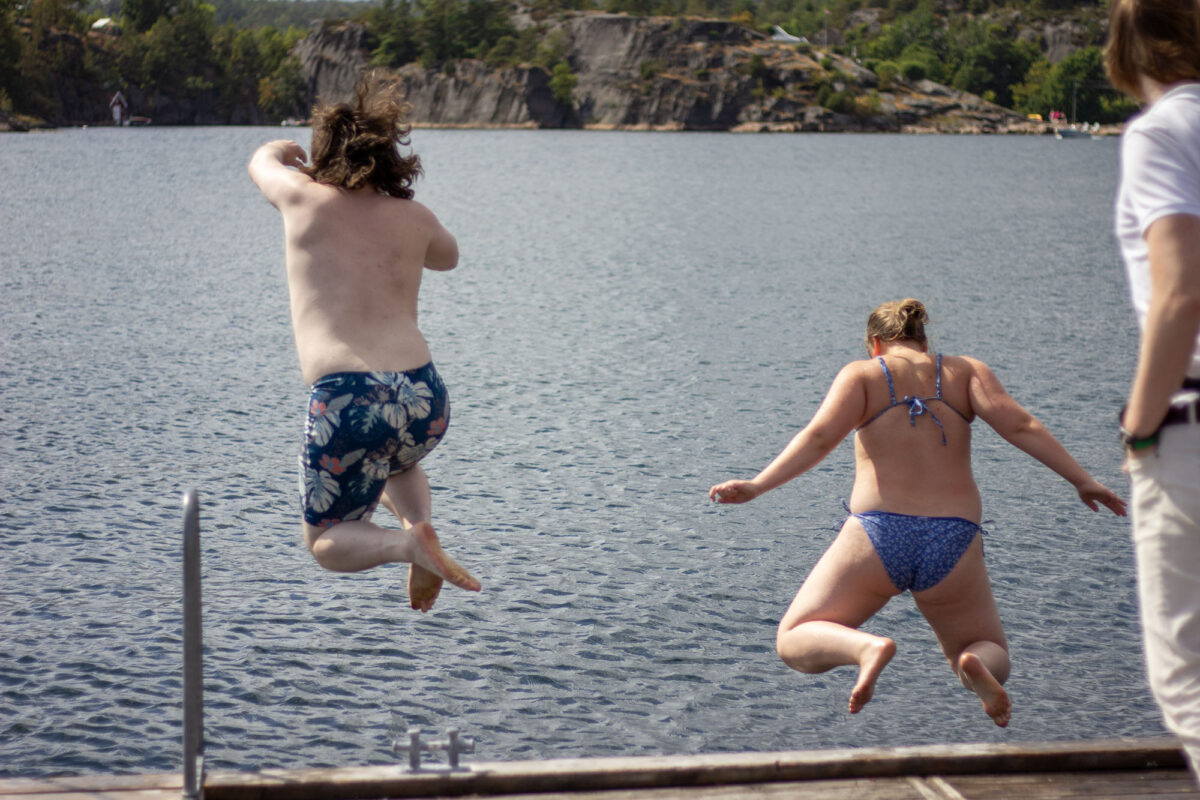 To personar som hoppar frå ei brygge.