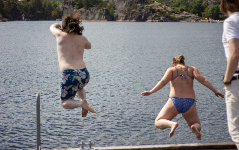 To personar som hoppar frå ei brygge.