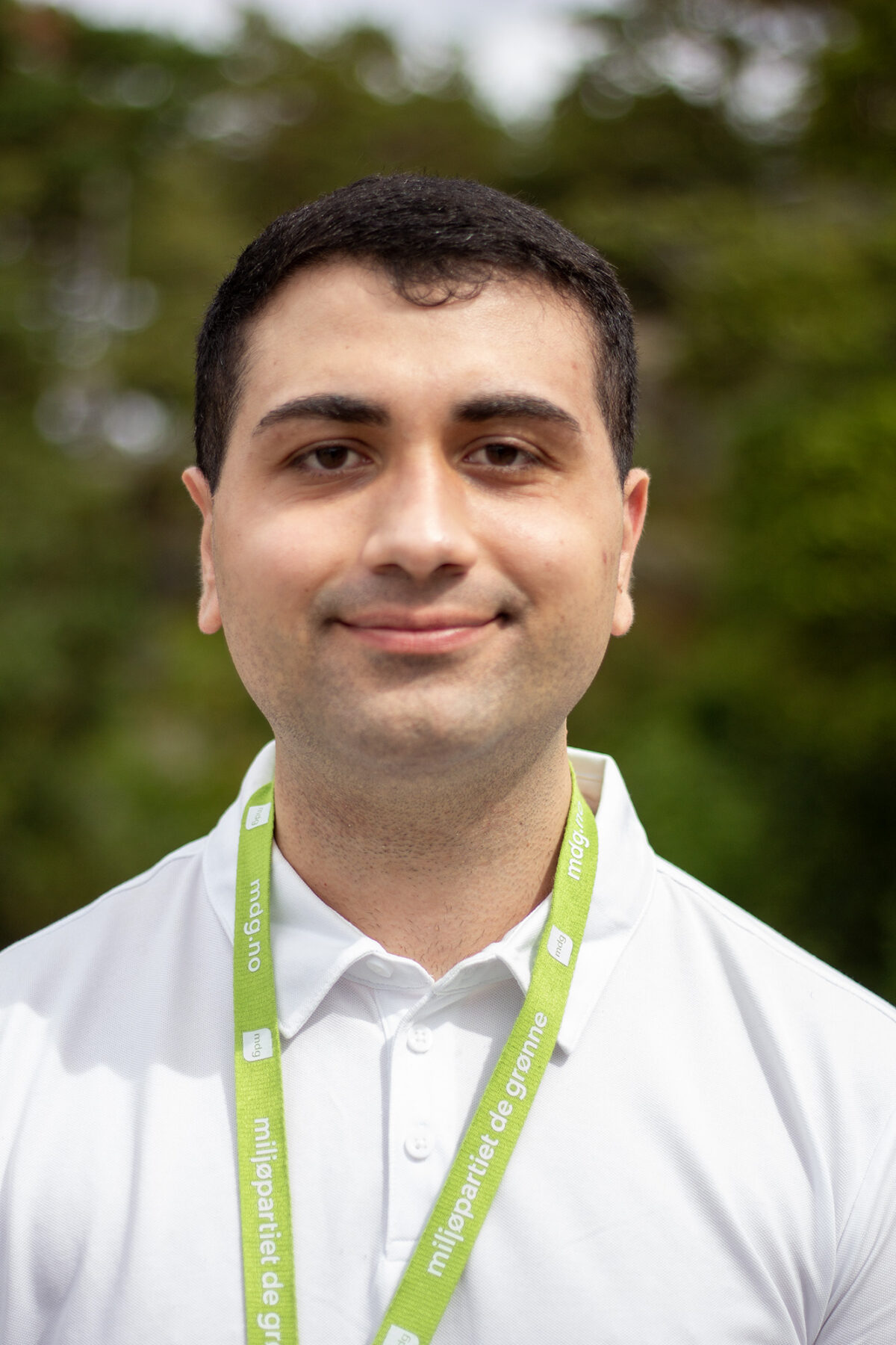 Ung mann med kvit skjorte, mørkt hår og grønt band.